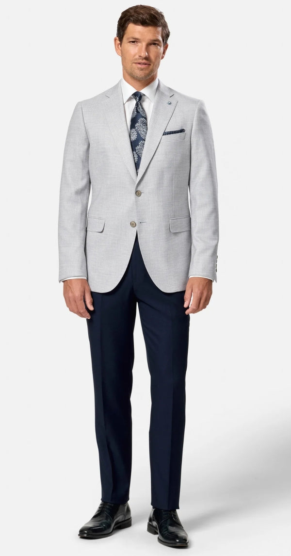Man wearing a light gray suit with navy pants on a white background