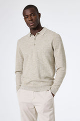 Man wearing a light beige sweater and white pants on a white background