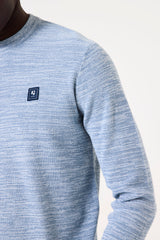 Close-up of a blue sweater with a brand logo on a white background