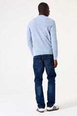 Man wearing a light blue striped sweater and dark blue jeans on a white background