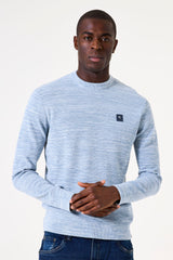 Man wearing a light blue sweater with a small logo on a white background