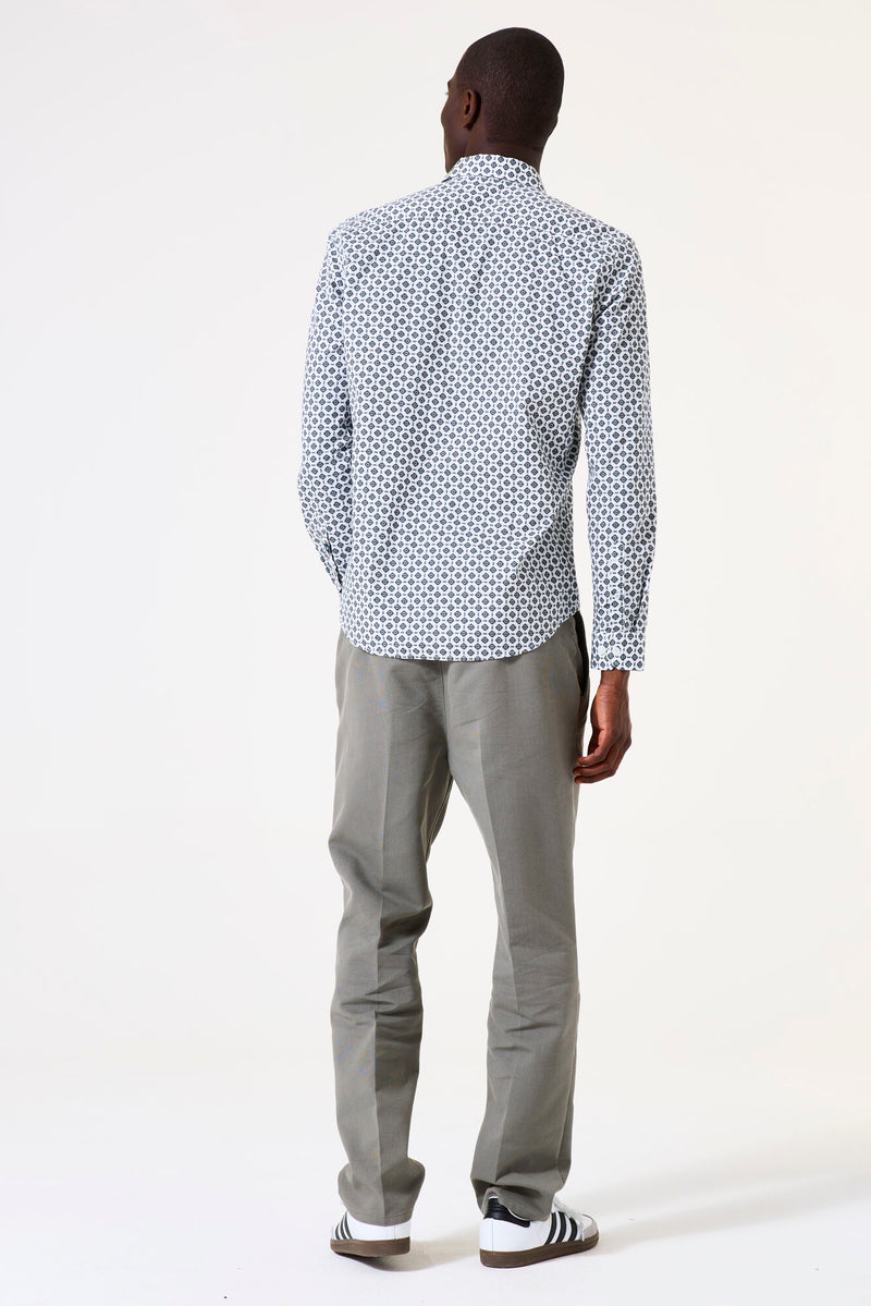 Man wearing a patterned shirt and gray pants on a white background
