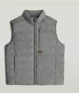 A light gray sleeveless puffer vest with a stand-up collar, front zipper, and a vertical zippered chest pocket, shown flat against a light gray background.